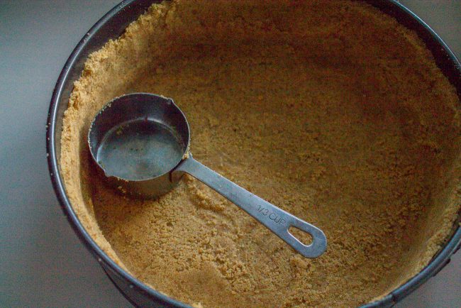 pressing graham cracker crust into a springform pan.