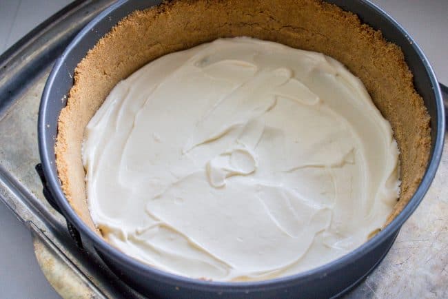 adding cheesecake filling to a graham cracker crust. 