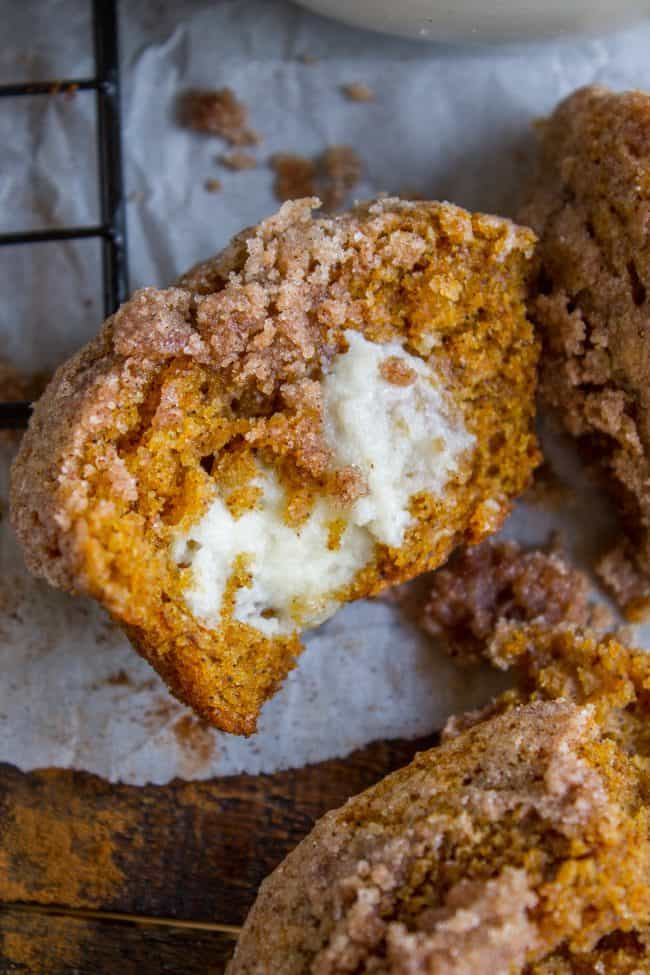 Pumpkin Cream Cheese Muffins from The Food Charlatan. There is no better way to welcome fall than with these Pumpkin Cream Cheese Muffins! A moist, tender, ultra pumpkin-y muffin, filled with sweetened cream cheese, and topped with cinnamon sugar crunch topping! They are irresistible! If it's too hot where you are, these muffins are guaranteed to make the leaves start falling off your trees. #muffin #pumpkin #fall #fallbaking #creamcheese #filling #filled #crumbtopping #topping #best #moist #cinnamon #pumpkinpie #pumpkinpiespice #thanksgiving #autumn #starbucks #copycat #tall #baking pumpkin cream cheese muffin split in half, shot from the side.