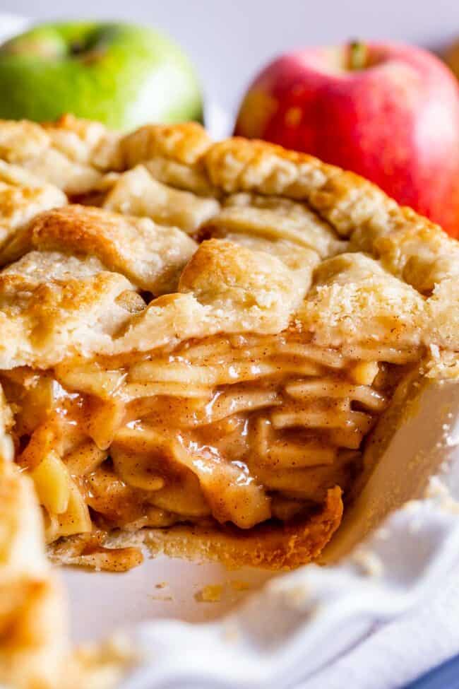 a tall apple pie with a golden brown crust and a slice cut out.