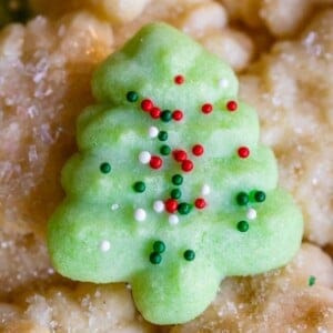 green almond spritz cookie in a tree shape with sprinkles on top