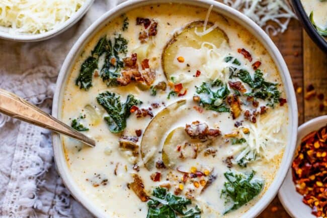 Zuppa Toscana Copycat (Sausage, Potato, and Kale Soup) From The Food Charlatan. Zuppa Toscana is a rich and creamy, soul-satisfying soup made with Italian sausage, potatoes, and hearty kale. It’s a copycat recipe of the famous soup at Olive Garden. I could eat this stuff for days! #zuppatoscana #soup #easy #recipe #olivegarden #onepot #zuppa #toscana #copycat #copy #sausage #potatoes #creamy #cream #halloween #fallsoup #fall #hearty #kale #italiansausage #betterthan Zuppa toscana copycat recipe in a white bowl shot from overhead