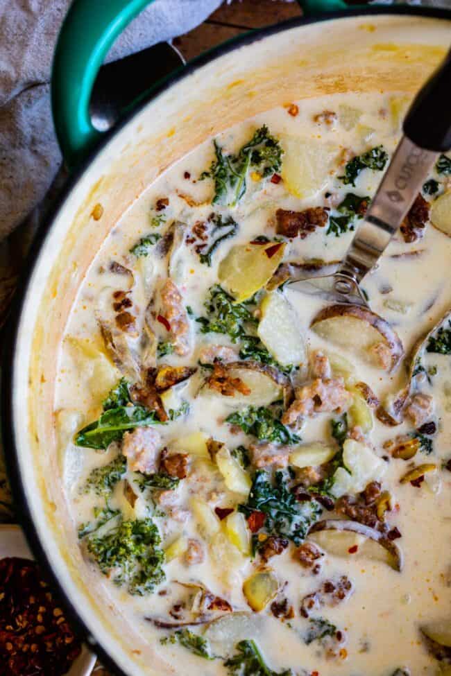 Zuppa Toscana Copycat (Sausage, Potato, and Kale Soup) From The Food Charlatan. Zuppa Toscana is a rich and creamy, soul-satisfying soup made with Italian sausage, potatoes, and hearty kale. It’s a copycat recipe of the famous soup at Olive Garden. I could eat this stuff for days! #zuppatoscana #soup #easy #recipe #olivegarden #onepot #zuppa #toscana #copycat #copy #sausage #potatoes #creamy #cream #halloween #fallsoup #fall #hearty #kale #italiansausage #betterthan Zuppa toscana recipe in a teal pot with a serving spoon