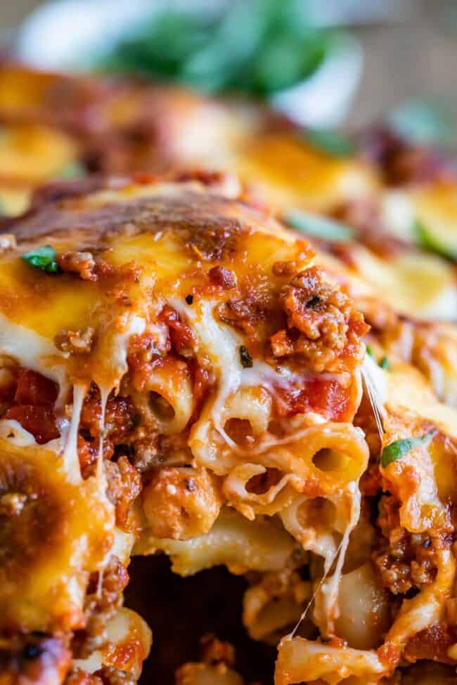 The Best Baked Ziti from The Food Charlatan. This recipe is a favorite! Italian sausage marinara, cottage cheese, and fresh basil combine to make this decadent casserole. The best part is the mozzarella that's chopped instead of shredded. They melt into pools of cheesy glory. We've always called it "Postpartum Ziti" because it makes a TON and is perfect for bringing to new moms! #bakedziti #pasta #ziti #easy #recipe #marinara #italiansausage #best #foracrowd #classic #cheesy #mozzarella baked ziti shot from the side.