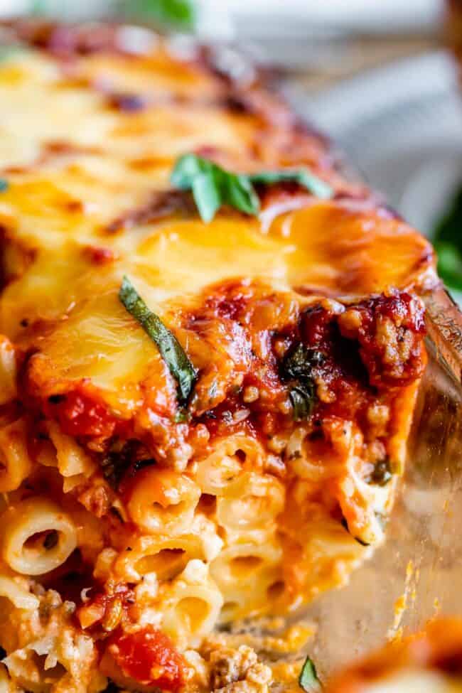 The Best Baked Ziti from The Food Charlatan. This recipe is a favorite! Italian sausage marinara, cottage cheese, and fresh basil combine to make this decadent casserole. The best part is the mozzarella that's chopped instead of shredded. They melt into pools of cheesy glory. We've always called it "Postpartum Ziti" because it makes a TON and is perfect for bringing to new moms! #bakedziti #pasta #ziti #easy #recipe #marinara #italiansausage #best #foracrowd #classic #cheesy #mozzarella baked ziti with cheese and fresh basil.