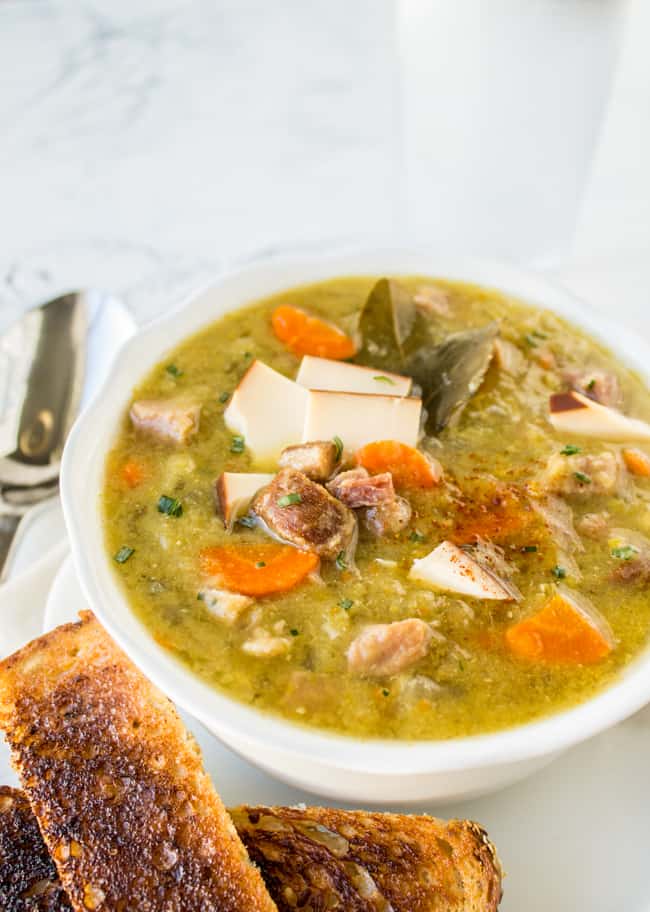 a bowl of split pea soup with ham and smoked gouda with toast strips.