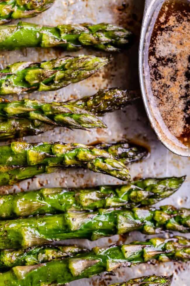 asparagus side on a sheet pan with a bowl of browned butter. 