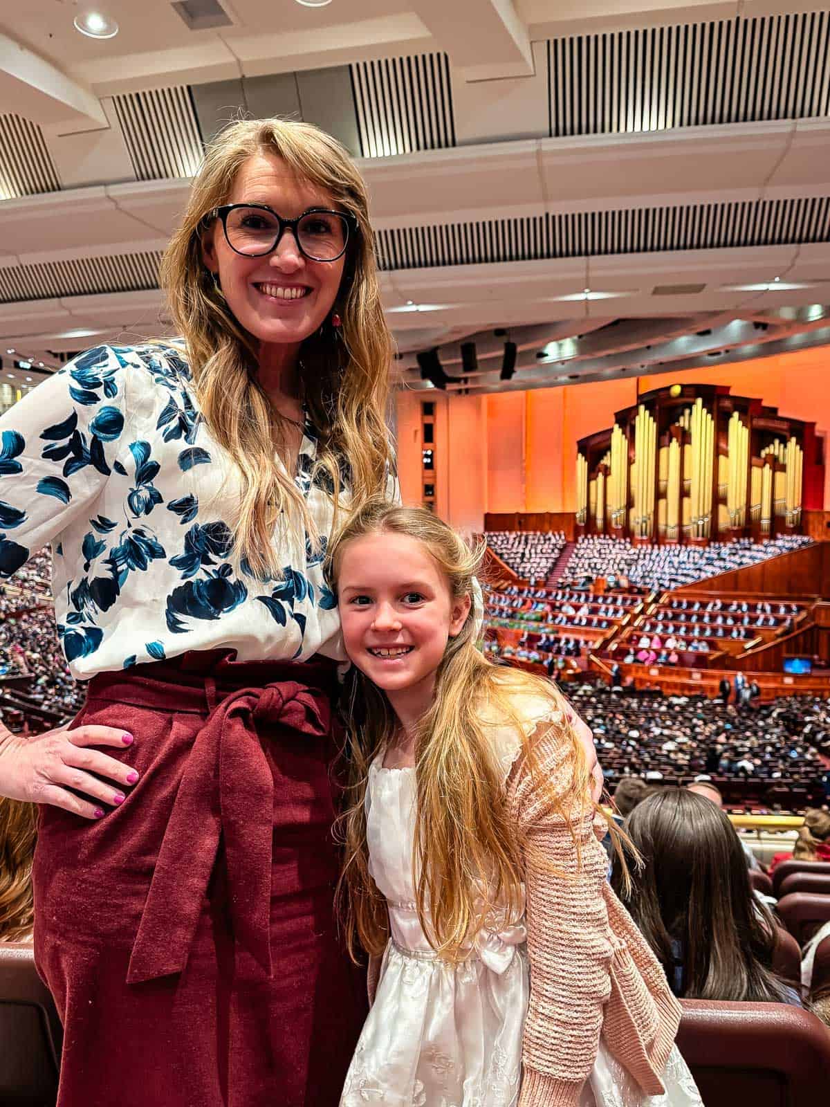 woman and girl standing in a large auditorium. 