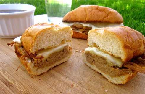 Cross section of cut french dip sandwiches on cutting board outside.