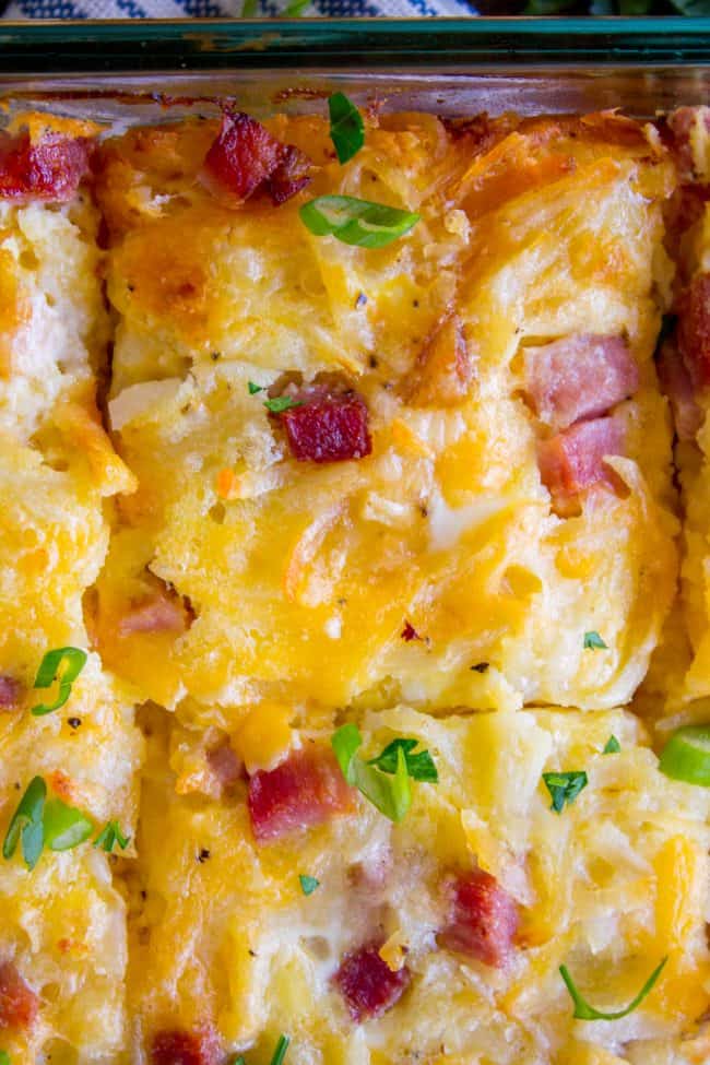 Cheesy Overnight Hashbrown Breakfast Casserole from The Food Charlatan. This Cheesy Hashbrown Breakfast Casserole is everything you need on Christmas morning! Hashbrowns are baked til crispy, then topped with eggs, cheese, and black forest ham. It's an overnight recipe to boot! Make ahead breakfasts ftw. #makeahead #cheese #breakfast #casserole #breakfastcasserole #easy #recipe #ham #blackforestham #Christmas #party #holildays #withhashbrowns #withpotatoes #overnight #makeahead #foracrowd #best hash brown potato casserole shot from above with slices cut into it.