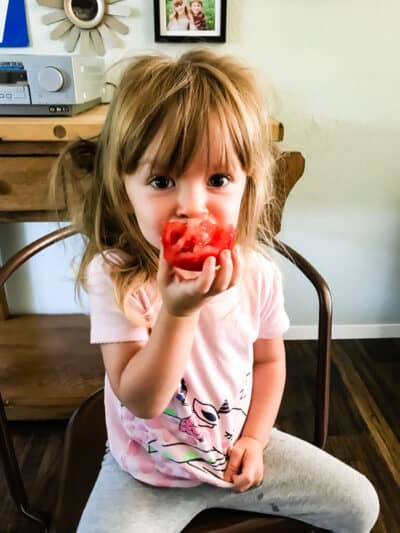cute little girl eating a tomato.