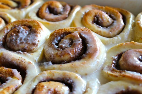 a pan of fresh baked cinnamon rolls with icing. 