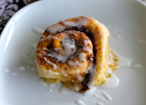 Cinnamon roll on a white plate with icing. 