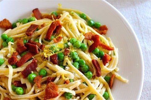 Pasta with creamy lemon sauce, bacon pieces, and green peas.