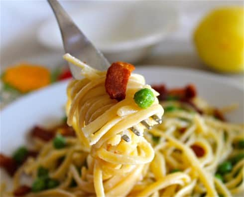 Bite of lemon bacon pasta on fork close up.