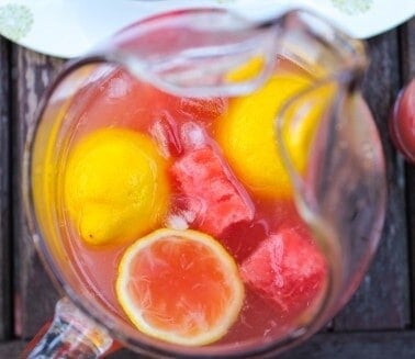 overhead shot of watermelon lemonade in pitcher on wood table.
