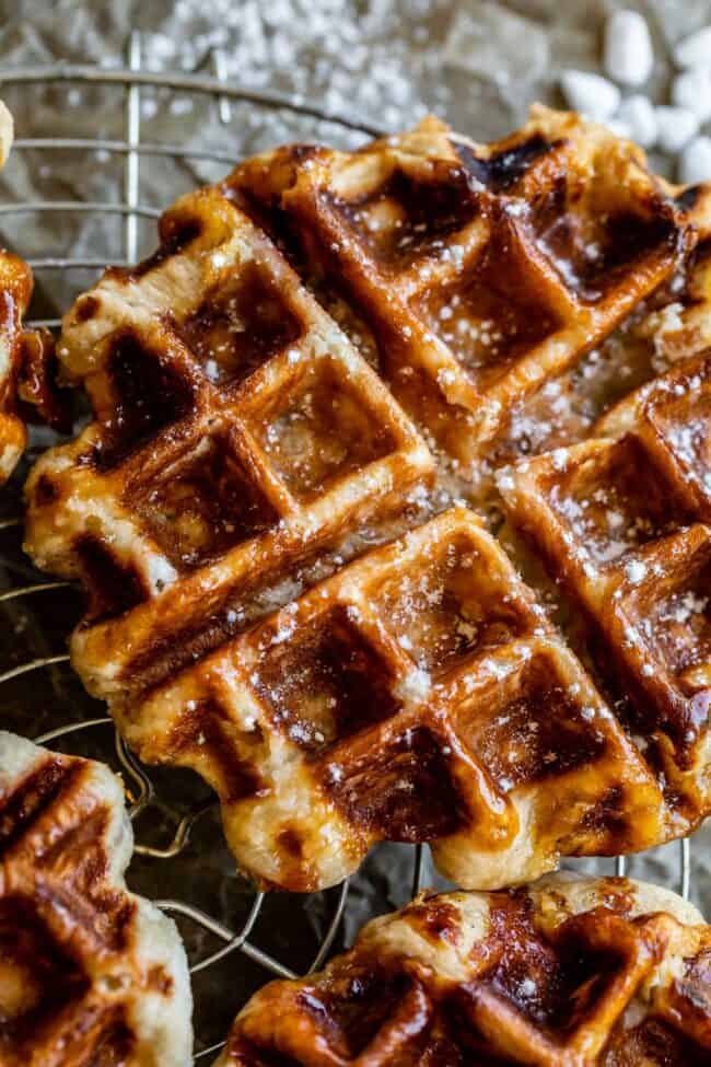 Liege Waffles with Pearl Sugar from The Food Charlatan. Liege waffles are made with a brioche-like yeast dough and are studded with pearl sugar. Pearl sugar is basically a small chunk of sugar that holds its shape as the waffles cooks, leaving you with gloriously crunchy bites of sugar. You can buy these on the street in Belgium and Norway. They make regular waffles look like amateurs. #liege #waffle #pearlsugar #belgium #syrup #maple #easy #recipe #breakfast #brunch #yeast #sugarwaffle liege waffles on a cooling rack.