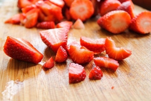 Sliced strawberries on a cutting board.