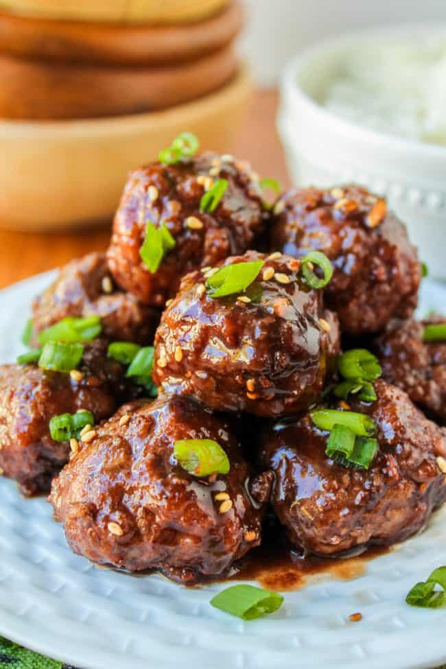 Meatballs with raspberry balsamic glaze stacked on plate with green onion garnish.