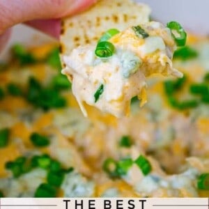 tortilla chip held in hand with cheesy buffalo chicken dip