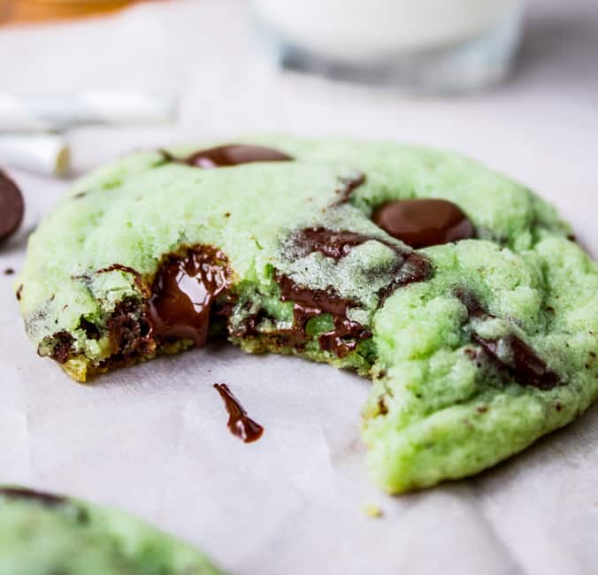 Mint Chocolate Chip Cookies from The Food Charlatan. These Mint Chocolate Chip Cookies are like eating the ice cream in the form of a warm, buttery, gooey cookie. They're crisp on the edges while perfectly tender and chewy in the center. #mint #chocolate #chip #cookies #peppermint #chocolatechip #gooey #chewy #easy #recipe #crisp A bite taken out of mint chocolate chip cookies
