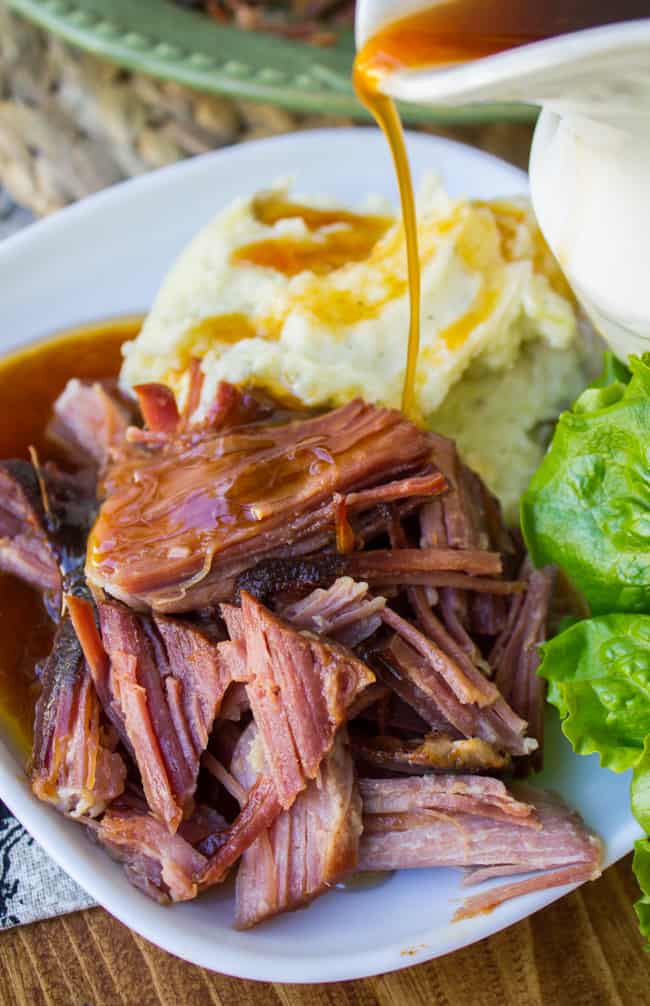 sriracha ham, mashed potatoes and a salad on a plate with gravy drizzled on the ham.