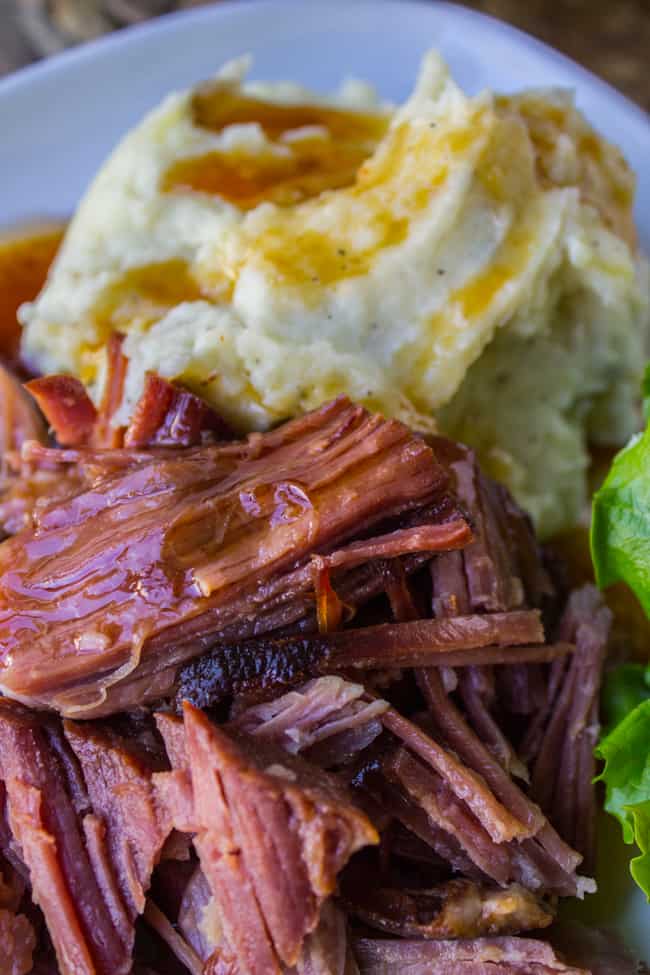 slow cooked ham, mashed potatoes and salad on a plate.
