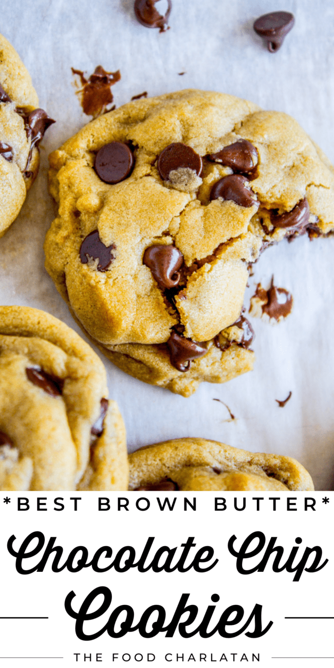 a chocolate chip cookie with a bite taken out of it on parchment paper and other cookies nearby.
