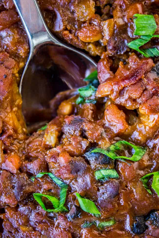 a serving spoon in a pan of bacon baked beans.