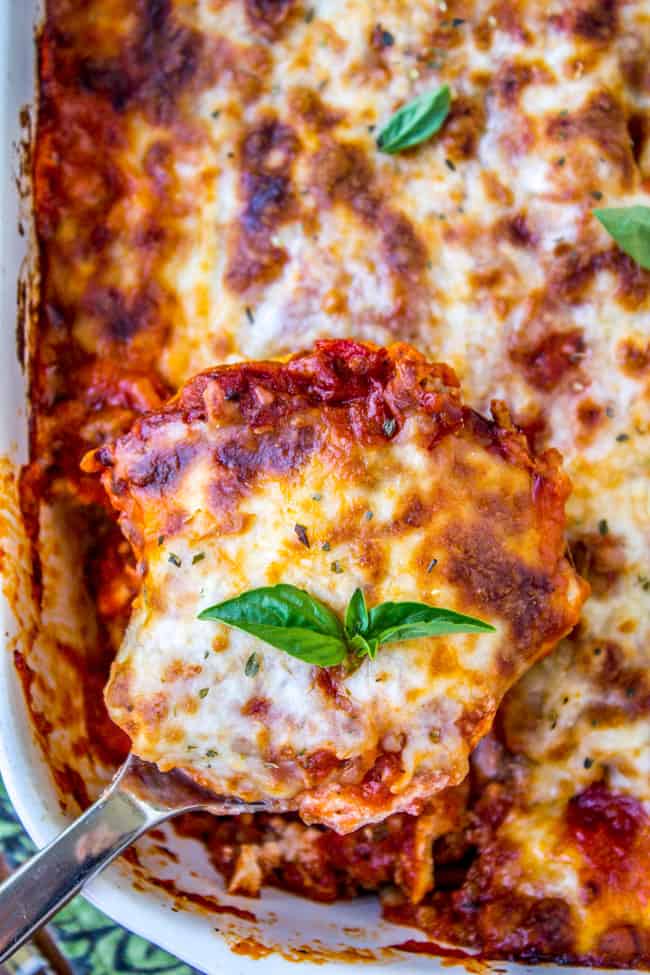 Easy Ravioli Lasagna from The Food Charlatan. This easy ravioli lasagna bake is a hearty no-brainer dinner to make on busy back-to-school nights. You don't even have to cook the ravioli, just throw it in frozen. It's a total crowd-pleaser! And a great make-ahead meal too. #ravioli #lasagna #frozen #quickdinner #ricotta #easy #cheese #mozzarella #marinara #freezermeal #makeahead ravioli lasagna with fresh basil on top.