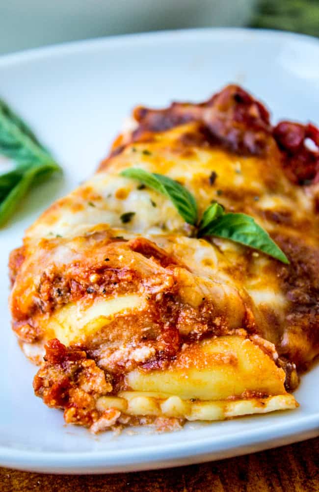 Easy Ravioli Lasagna from The Food Charlatan. This easy ravioli lasagna bake is a hearty no-brainer dinner to make on busy back-to-school nights. You don't even have to cook the ravioli, just throw it in frozen. It's a total crowd-pleaser! And a great make-ahead meal too. #ravioli #lasagna #frozen #quickdinner #ricotta #easy #cheese #mozzarella #marinara #freezermeal #makeahead a piece of ravioli lasagna.