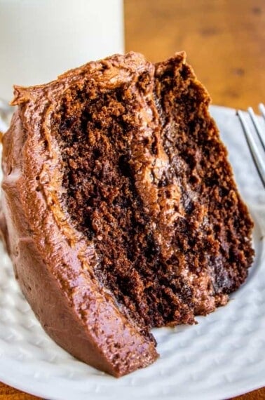 chocolate cake with chocolate frosting on a white plate.