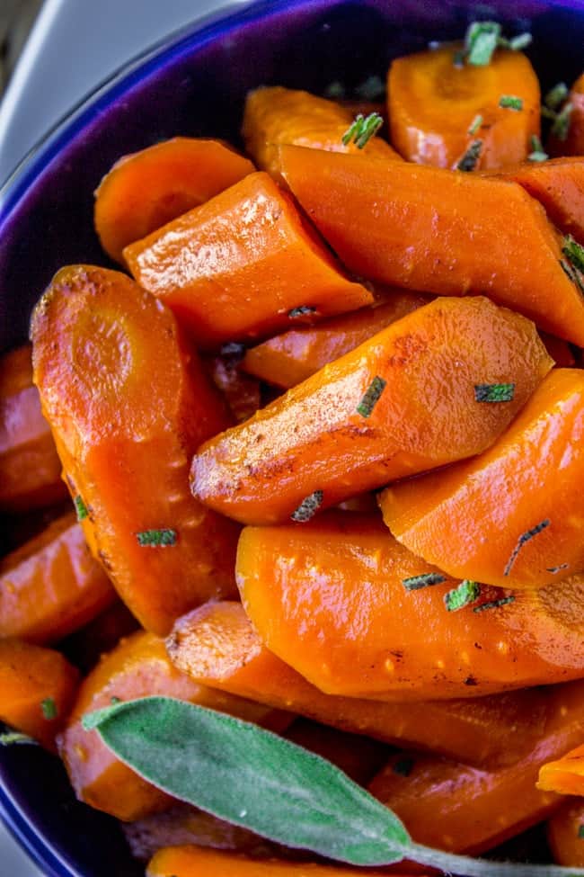 Glazed Carrots in a blue bowl with herbs. 
