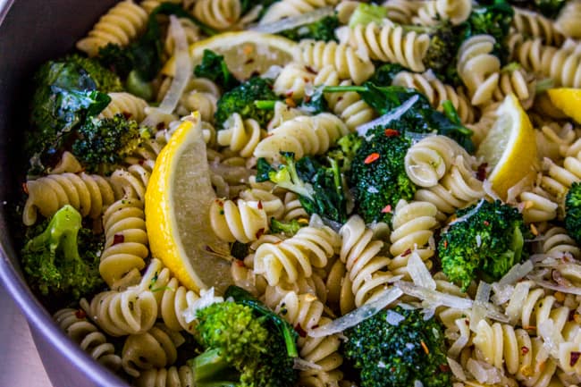 closeup overhead of a pot full of broccoli and pasta with lemons.