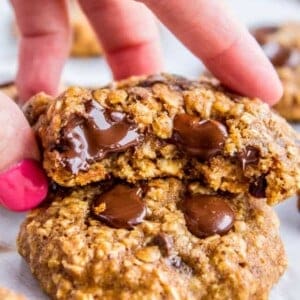 oatmeal chocolate chip cookies with bite taken out and hand lifting it