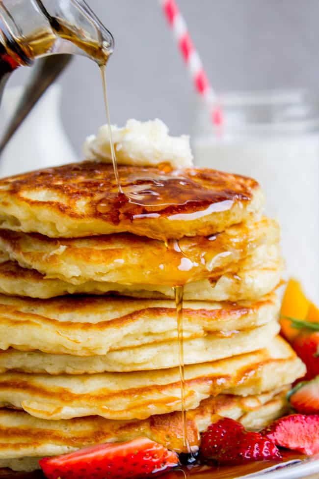The Best Pancakes I've Ever Made from The Food Charlatan. EUREKA! The Best Pancakes Ever. Guys, I'm not even kidding when I say I've been looking for this buttermilk pancake recipe for my entire life. They are fluffy, crispy on the edges, tender in the middle, and completely stackable. The search is over!! #pancakes #buttermilk #fluffy #crispyedges #easy #fromscratch #sourcream #delicious #breakfast #brunch Pancakes stacked with butter on top and syrup running down the side and strawberries on the plate.