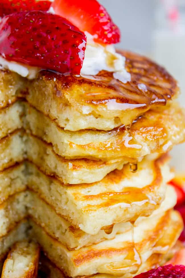 The Best Pancakes I've Ever Made from The Food Charlatan. EUREKA! The Best Pancakes Ever. Guys, I'm not even kidding when I say I've been looking for this buttermilk pancake recipe for my entire life. They are fluffy, crispy on the edges, tender in the middle, and completely stackable. The search is over!! #pancakes #buttermilk #fluffy #crispyedges #easy #fromscratch #sourcream #delicious #breakfast #brunch Delicious pancakes with syrup, strawberries, and butter on top, showing a stack of pancakes with a slice missing.