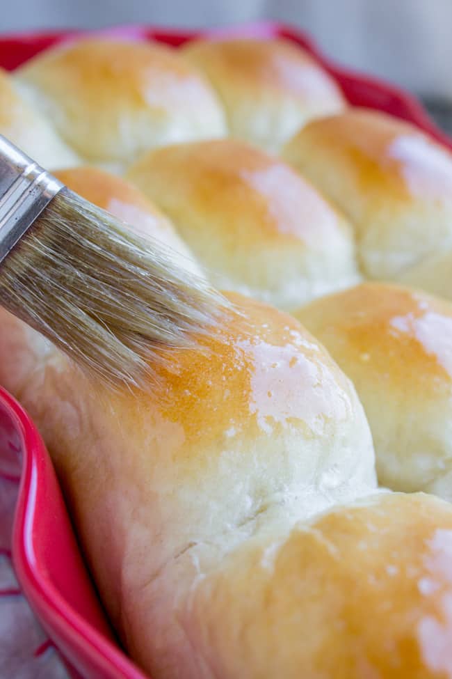 Brushing butter on homemade dinner rolls.