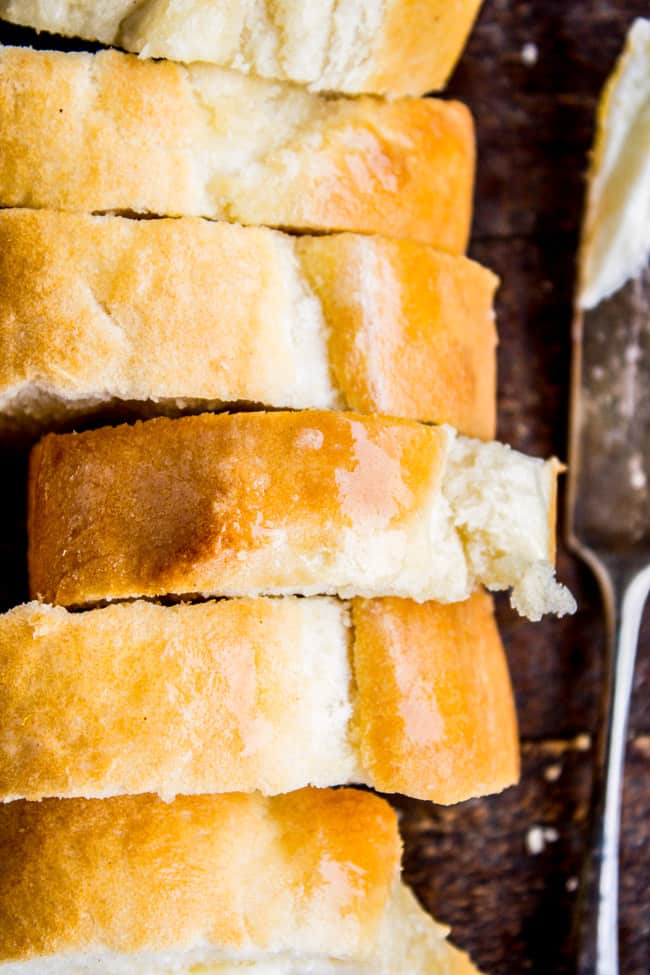 One Hour French Bread from The Food Charlatan. This delicious yeasty French bread recipe has only one 20-minute rise before going into a screaming hot oven for another 20 minutes. At the end you have golden crusty goodness just waiting to be slathered in butter or dipped in oil and balsamic! One hour, I promise!! #french #bread #homemade #easy #ideas #baguette #quick sliced loaf of homemade French bread.