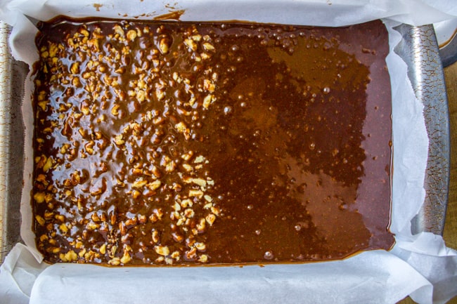 brownie batter in a pan, half with walnuts, half without.