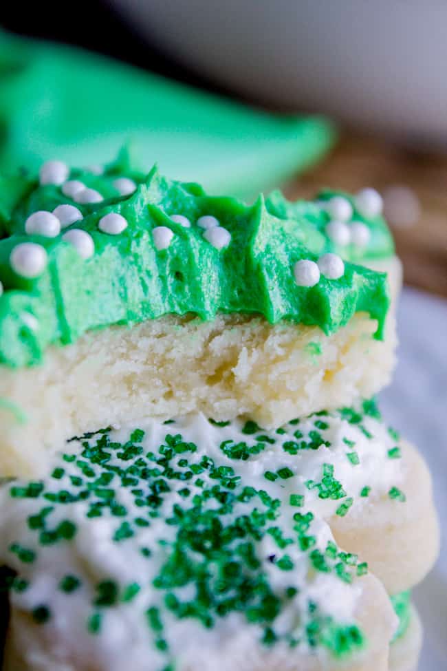 Green frosting for cookies with sprinkles on top of cookie with bite taken out of it.