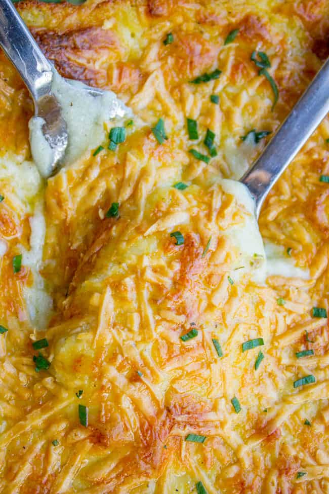 Cheesy make ahead mashed potatoes in a large pan with serving spoons. 