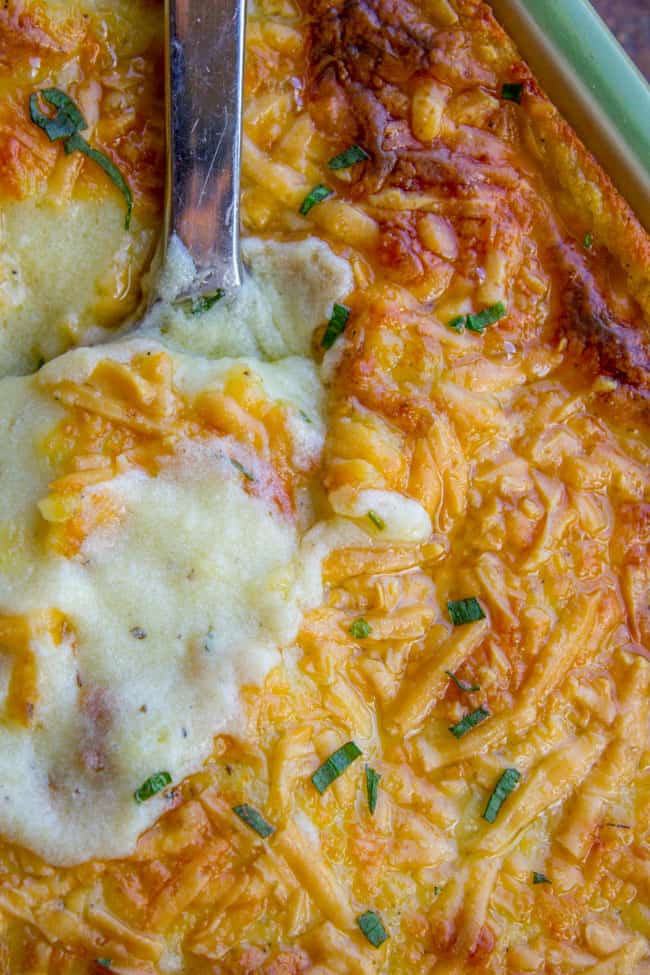 Golden brown mashed potatoes in a large pan with spoon. 