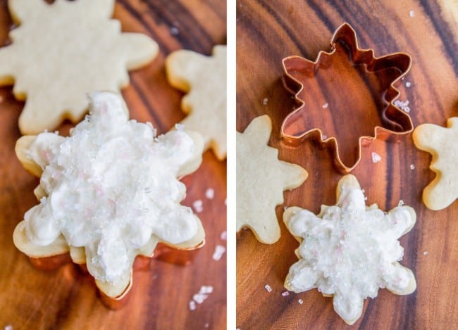 white-frosted snowflake cookies next to a metal cookie cut out.