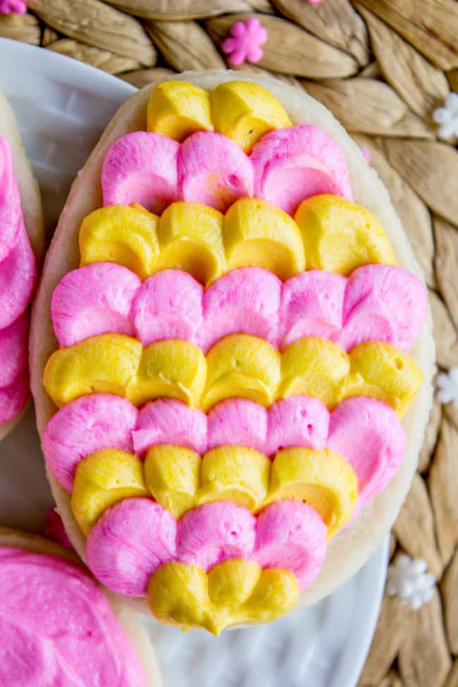 egg-shaped soft sugar cookie with dollops of pink and yellow butter cream frosting.