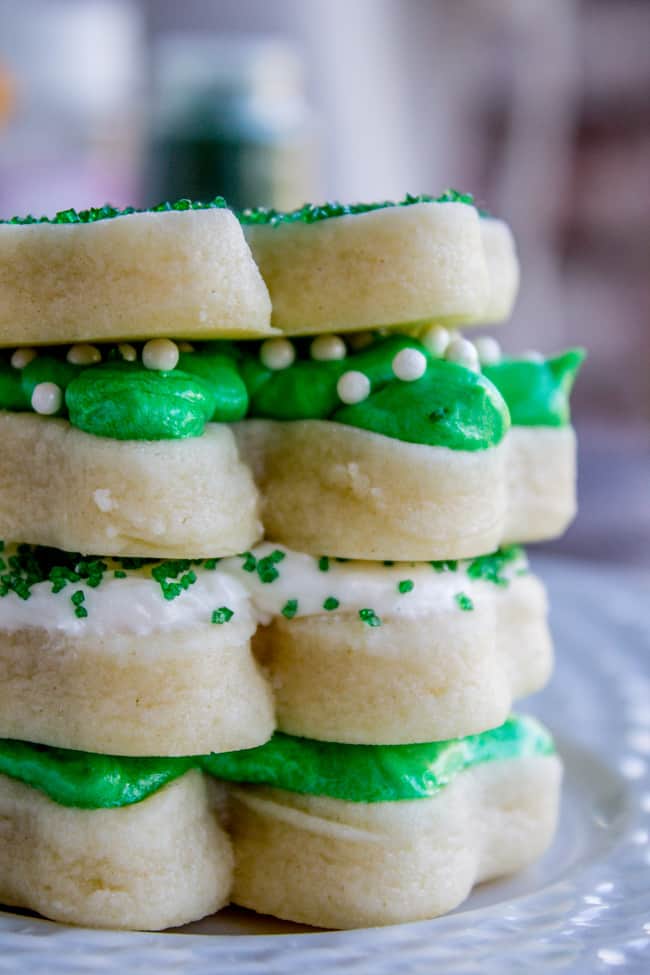 soft frosted sugar cookies stacked, frosted with green and white buttercream frosting and sprinkles.