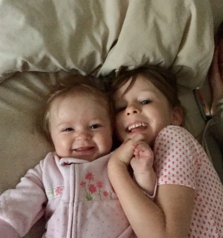 two kids smiling in a bed. 