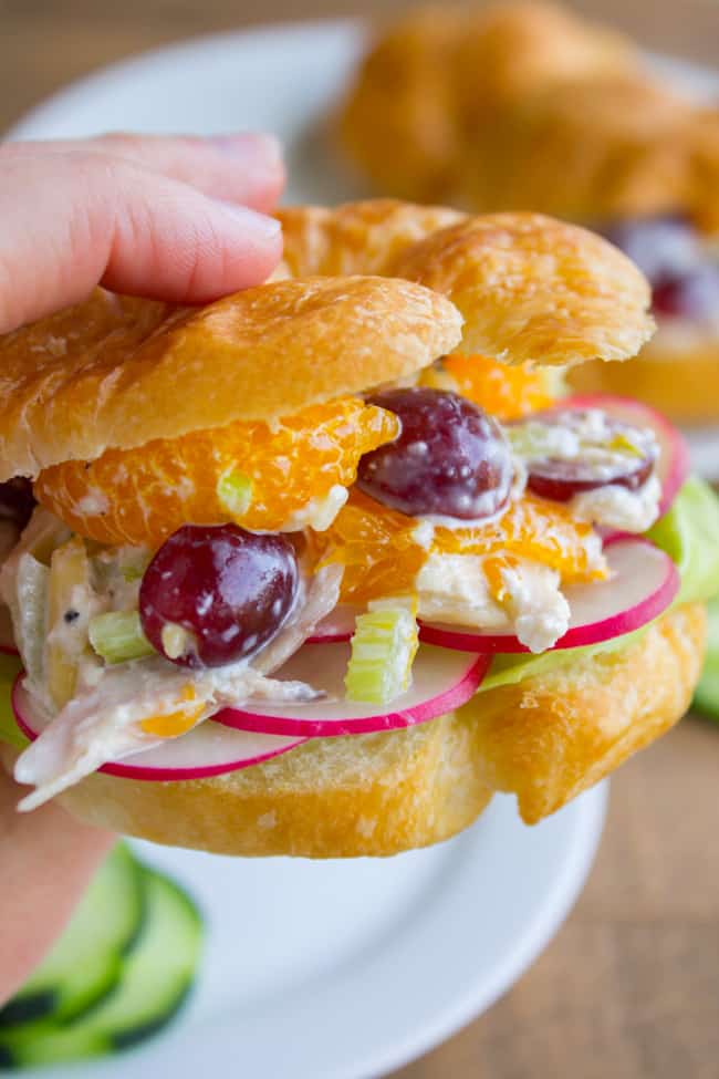 a hand holding a chicken salad croissant sandwich.
