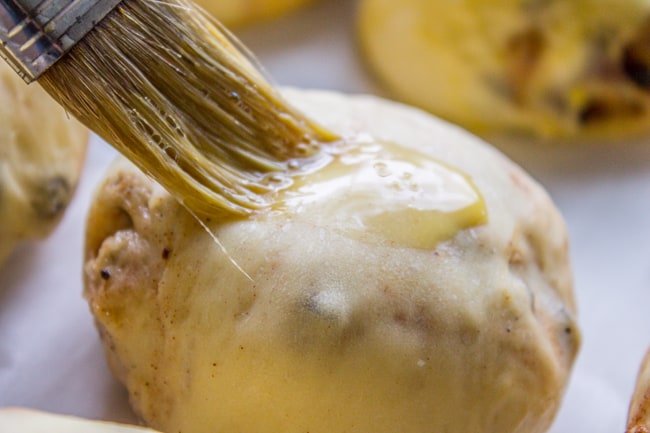 brushing a hot cross bun with egg wash.