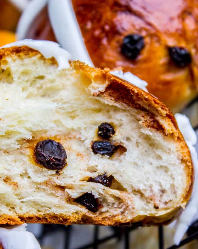 a hot cross bun cut in half showing currants in fluffy dough.